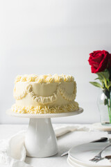 Piping buttercream on Vintage cake on a cake plate, Frilly Cake covered in yellow frosting, process...