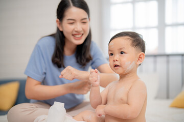 Mom enjoys playful bonding time with her baby during bath preparation in a cozy room setting