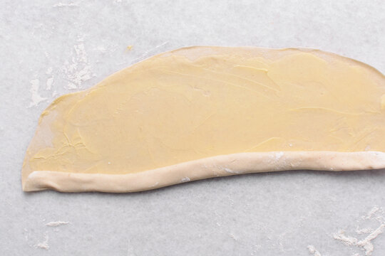 Overhead view of rolled paratha dough on a marble countertop, top view of flaky flatbread dough, process of making paratha