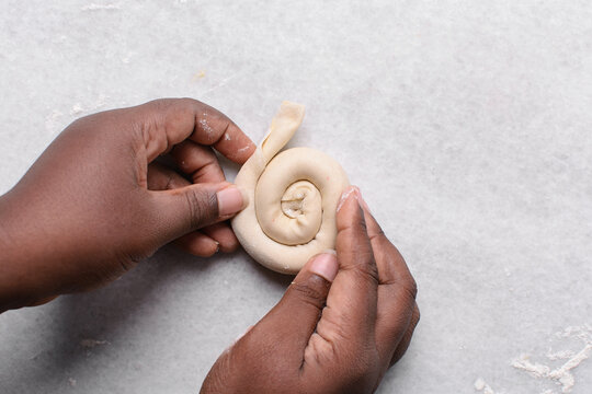 Overhead view of rolled paratha dough on a marble countertop, top view of flaky flatbread dough, process of making paratha