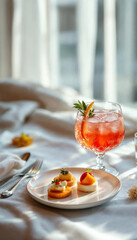 Elegant cocktail and gourmet appetizer on white linen, bathed in soft natural light.









