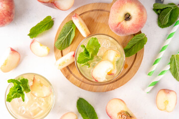 Flat peach lemonade, iced tea or mojito cocktail with fresh fruit garnish. Sweet non-alcohol flat chinese donuts fig peach mocktail with peach slices, mint and crushes ice