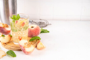 Flat peach lemonade, iced tea or mojito cocktail with fresh fruit garnish. Sweet non-alcohol flat chinese donuts fig peach mocktail with peach slices, mint and crushes ice