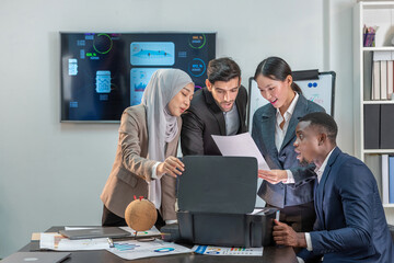A group of multi-ethnic business people are working together in an office. They are looking at a...