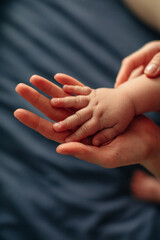 Little cute baby hand in mother's hand, concept of cozy and happy childhood and motherhood