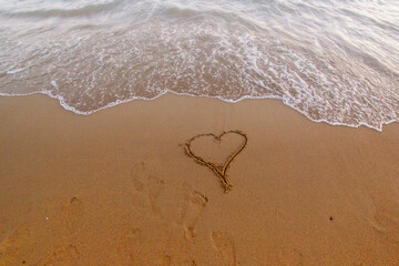 a heart shape drawn on the sandy beach near the shoreline, with gentle waves approaching, symbolizing love, romance, and the peaceful beauty of the sea and nature’s calm moments.

