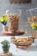 A creative food composition featuring a bag of fried macaroni crispy snack placed on a wooden stand, with pieces of the snack artistically scattered on a wooden plate in the foreground. 