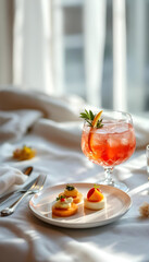 Elegant cocktail and gourmet appetizer on white linen, bathed in soft natural light.









