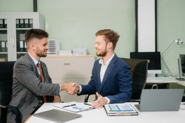Two office colleagues discuss ideas for a startup project in a modern workspace, using laptops and smartphones