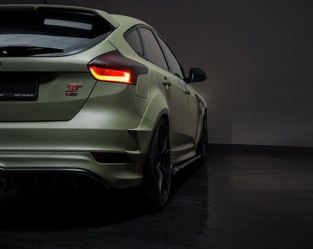 Olive Focus ST in dark garage. Rear right side view of satin green Ford hatchback car in empty room at night. Ukraine, March 6 2017.