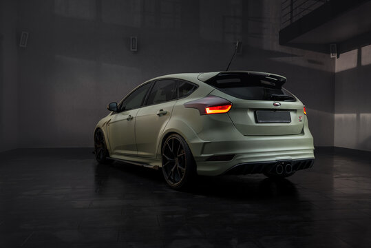 Olive Focus ST in dark garage. Rear three quarter view of satin green Ford hatchback car in empty room at night. Ukraine, March 6 2017.