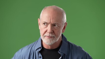 A mature man with a beard is making a shushing gesture with his finger on his lips, portrayed against a vibrant green screen background.
