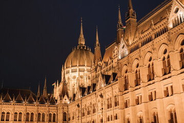 The Hungarian Parliament Building in Budapest glows at night, showcasing neo Gothic architecture...