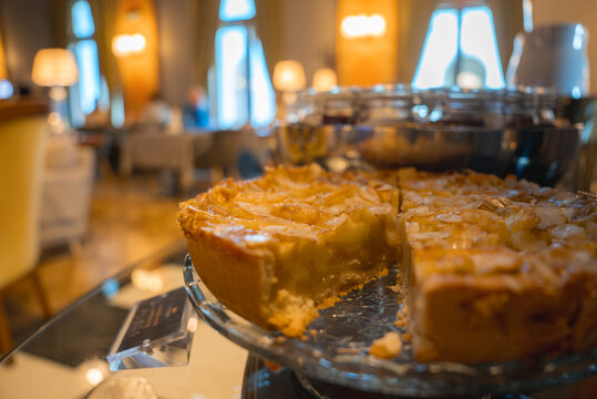 A partially sliced pie with a golden crust and glossy filling on a glass plate, set against a boutique hotel interior with warm lighting and arched windows.