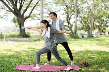 Couple practicing yoga poses together in the park
