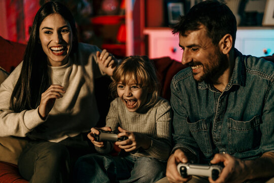 Happy family playing videogames together on the sofa at home