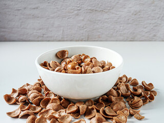 Chocolate corn flakes with milk in a bowl on white background