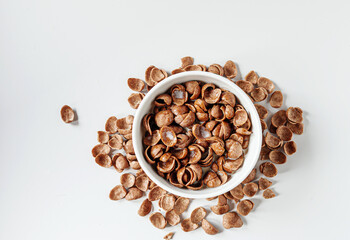 Chocolate corn flakes with milk in a bowl on white background, Top view