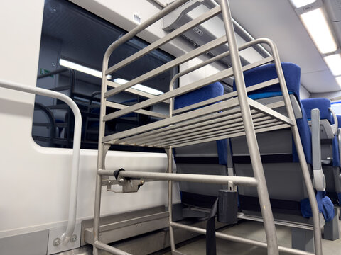 Sturdy metal luggage rack with securing strap ensures passenger safety and reliable baggage storage on board a high-speed train, minimizing risk of movement during transit