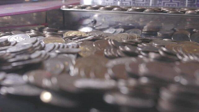 Piles of quarters in pushing arcade game 4k
