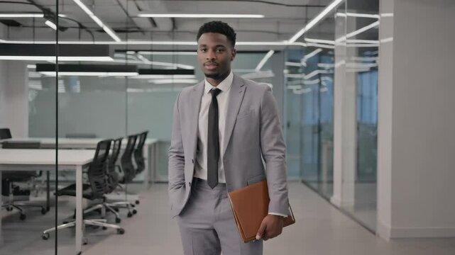 A confident African-American businessman waiting for negotiations in the office with a folder in his hands