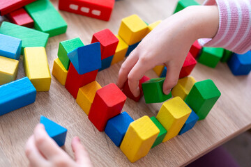 Child fun playing with wooden toys, play time, Colorful blocks and figures on table. Early education, fine motor skills concept