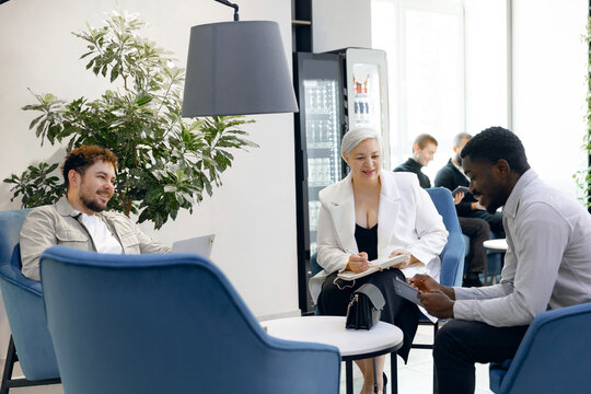 Diverse team in bright, modern office lounge having collaborative meeting. natural light, contemporary furniture, and relaxed atmosphere enhance creativity and communication.