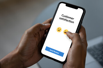 Person using smartphone app to provide customer satisfaction feedback emojis review