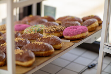 Colorful donuts and glazed pastries on a wooden tray in bakery