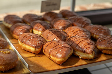 Many chocolate croissants displayed on wooden tray in bakery shop.