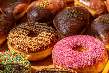Assorted glazed and decorated donuts on a wooden tray in a bakery