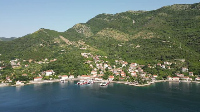 Aerial view of the ferry terminal in Kamenari, in a picturesque part of the Bay of Kotor in Montenegro, with a mountain backdrop and vibrant summer scenery