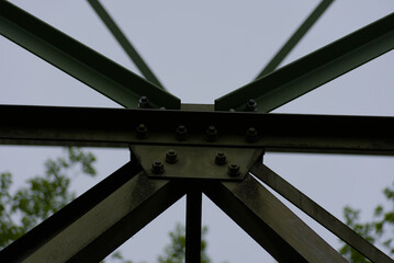 An imposing metal structure's bolted connections highlight industrial strength and precision against a stark sky, showcasing engineering detail
