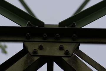 An imposing metal structure's bolted connections highlight industrial strength and precision against a stark sky, showcasing engineering detail