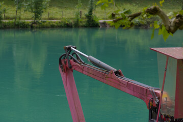 A robust hydraulic arm in bold red and silver stands against a calming teal backdrop, showcasing industrial power and precision