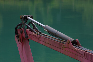 A robust hydraulic arm in bold red and silver stands against a calming teal backdrop, showcasing industrial power and precision