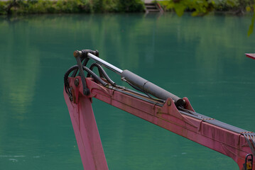 A robust hydraulic arm in bold red and silver stands against a calming teal backdrop, showcasing industrial power and precision