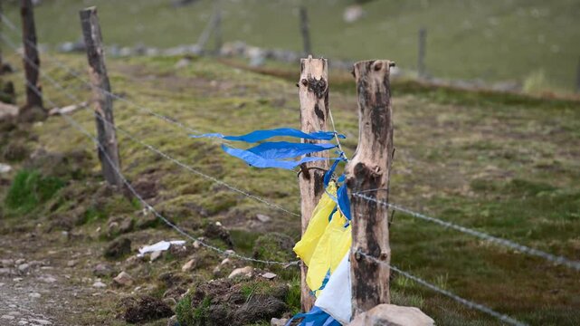 Colorful plastic bags tied on a rural fence along the Ausangate trekking trail in Peru, used by local herders to scare away animals.