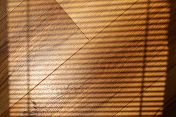 Shadows cast on hardwood flooring create a unique pattern in natural light during the afternoon...