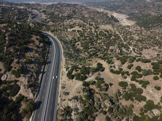 A drone view of South Türkiye's arid, Mediterranean-like hills with terra tones and sparse vegetation, captured during a scenic summer road trip