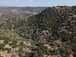 A drone view of South Türkiye's arid, Mediterranean-like hills with terra tones and sparse vegetation, captured during a scenic summer road trip