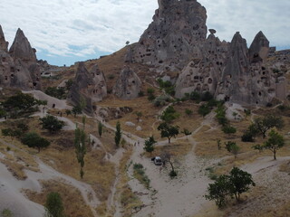 A drone view of G&ouml;reme in Cappadocia, revealing cave homes, fairy chimneys, and ancient landscapes bathed in soft light and rich earthy tones.