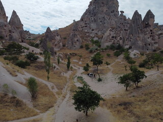 A drone view of G&ouml;reme in Cappadocia, revealing cave homes, fairy chimneys, and ancient landscapes bathed in soft light and rich earthy tones.