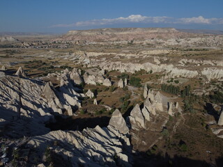 A stunning drone shot over Love Valley in Cappadocia, showcasing its iconic rock formations, surreal landscape, and warm tones under a clear sky.