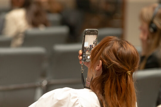 An individual captures a vivid image using a smartphone during a lively event, effectively highlighting the blend of engagement and modern technology used in contemporary public settings