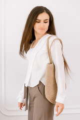 Woman carrying a stylish woven tote bag, showcasing casual chic fashion indoors