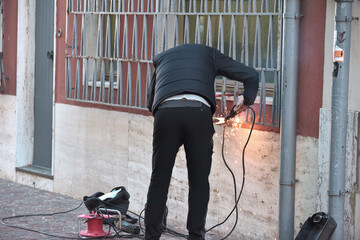  Tecnico saldatore taglia inferriata in strada urbana durante lavori di manutenzione
