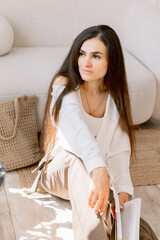 Portrait of elegant woman holding a book in cozy room