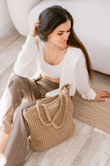 Elegant woman with long hair sitting and chilling with a woven tote bag