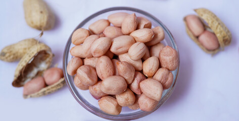 Raw Groundnuts in an glass bowl on white background. Peanuts isolated. Top angle peanuts bowl. Peanut isolated. Raw peanuts bowl.